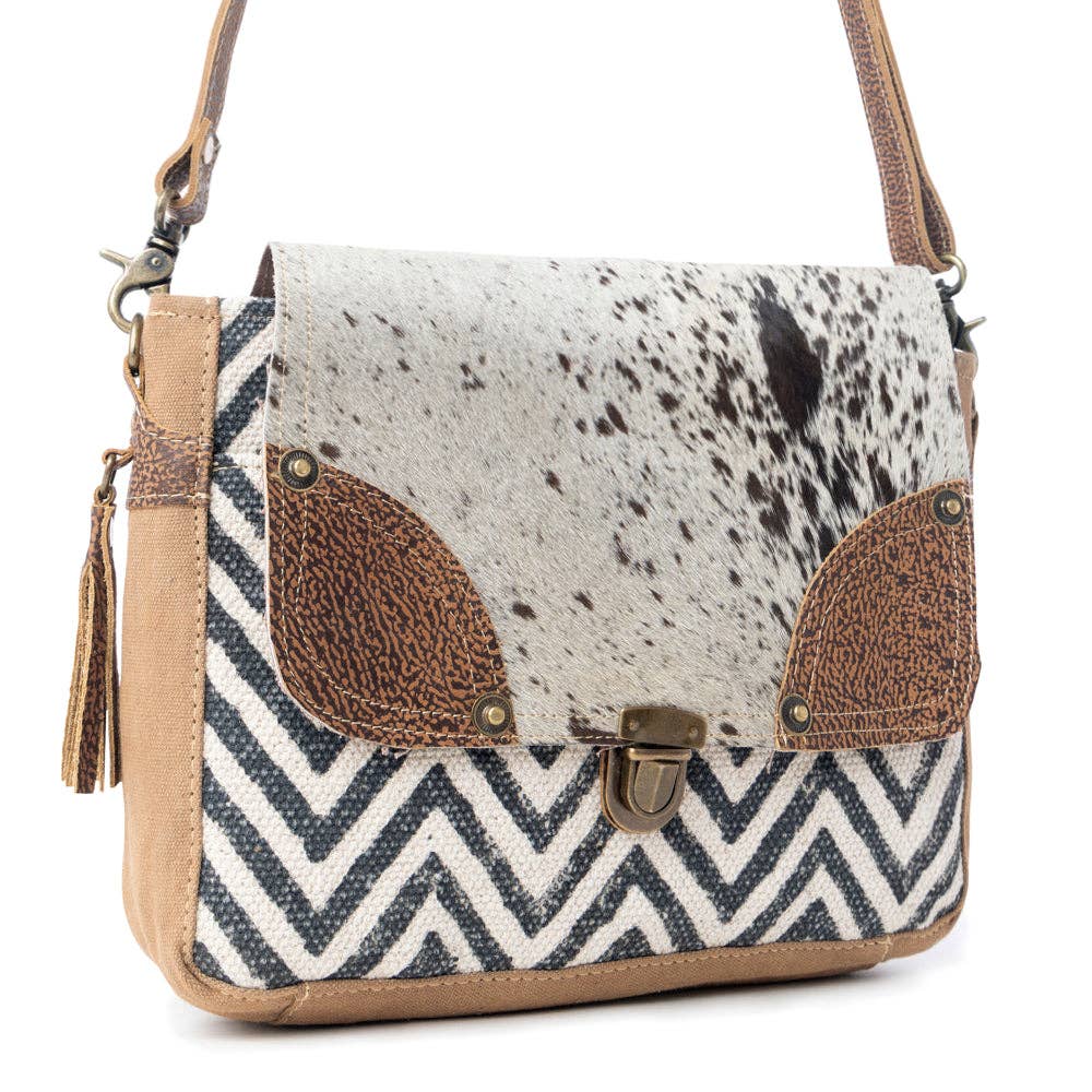 Rugged messenger bag featuring a spotted hairon flap, chevron design, and tan leather trim in shades of brown, cream, and black.