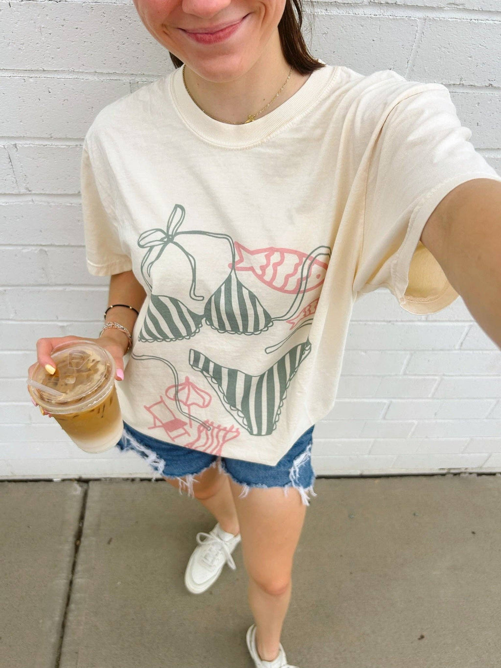 Loose-fitting ivory tee featuring a playful graphic design of various bikini styles, perfect for summer outings.