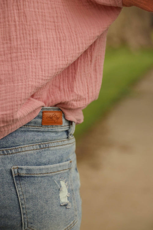 Denim skirt featuring a light wash and patched distressing on the front, designed for a comfortable fit with pockets.