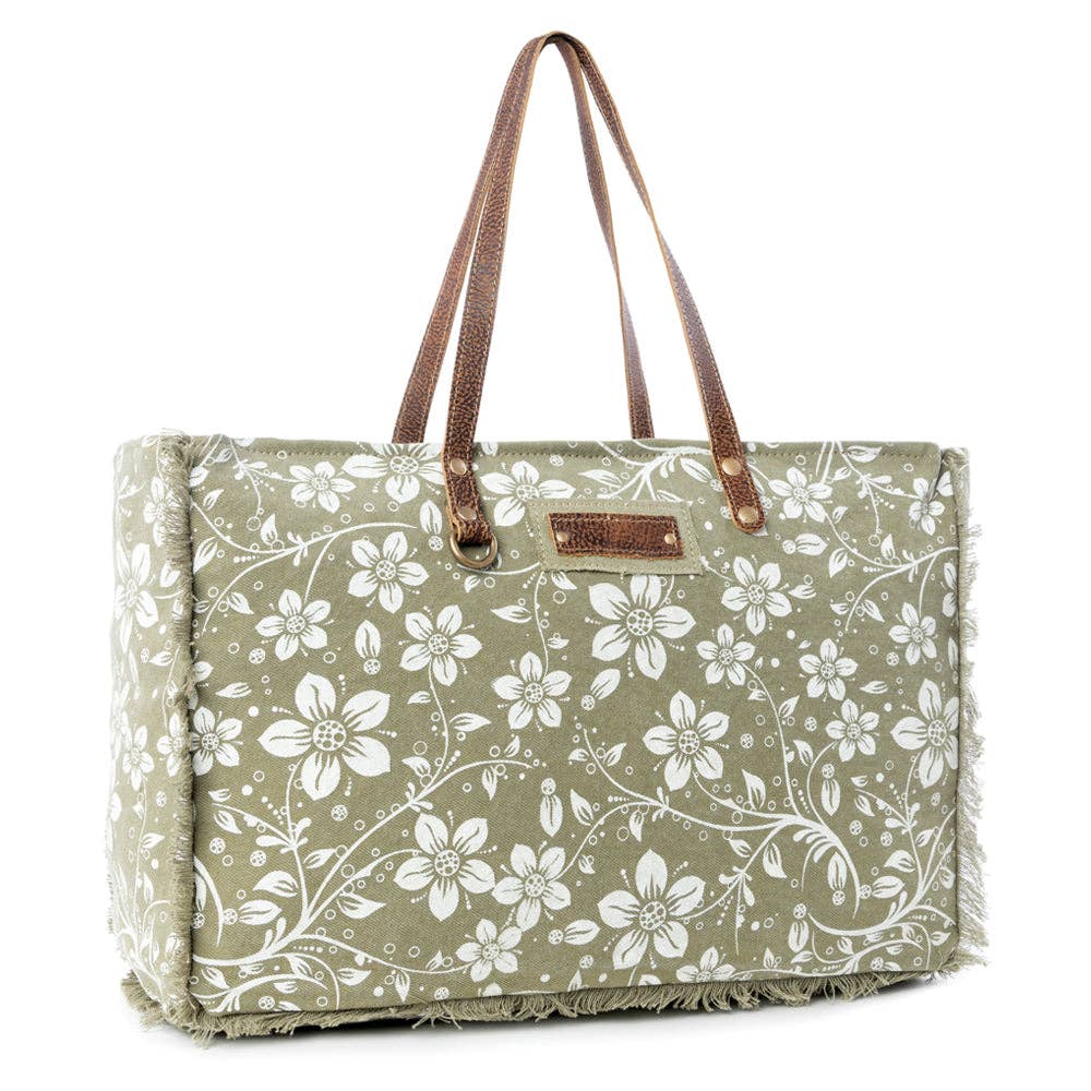 Floral weekender bag with leather top handles, showcasing a large main compartment and stylish stitching details.