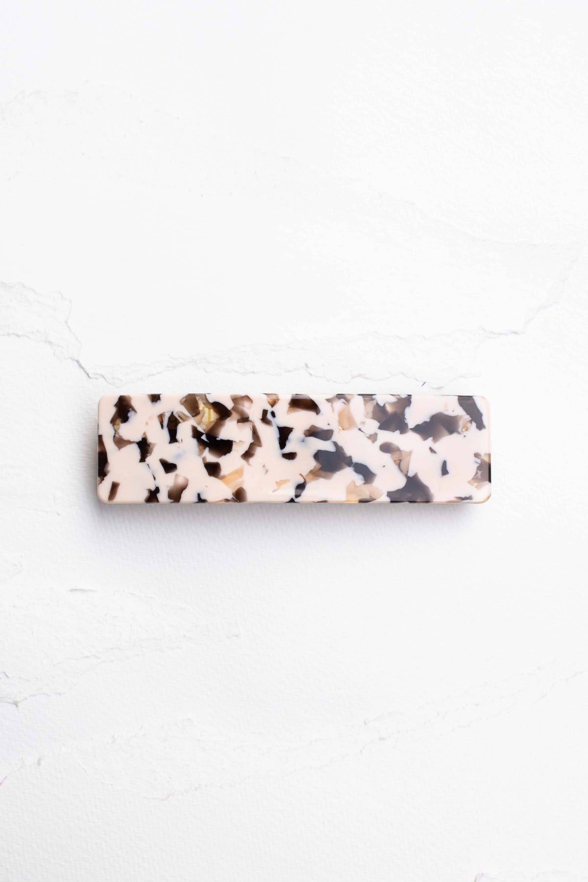 Rectangular hair barrette featuring a marbled pattern in shades of beige, brown, and cream with a glossy finish.