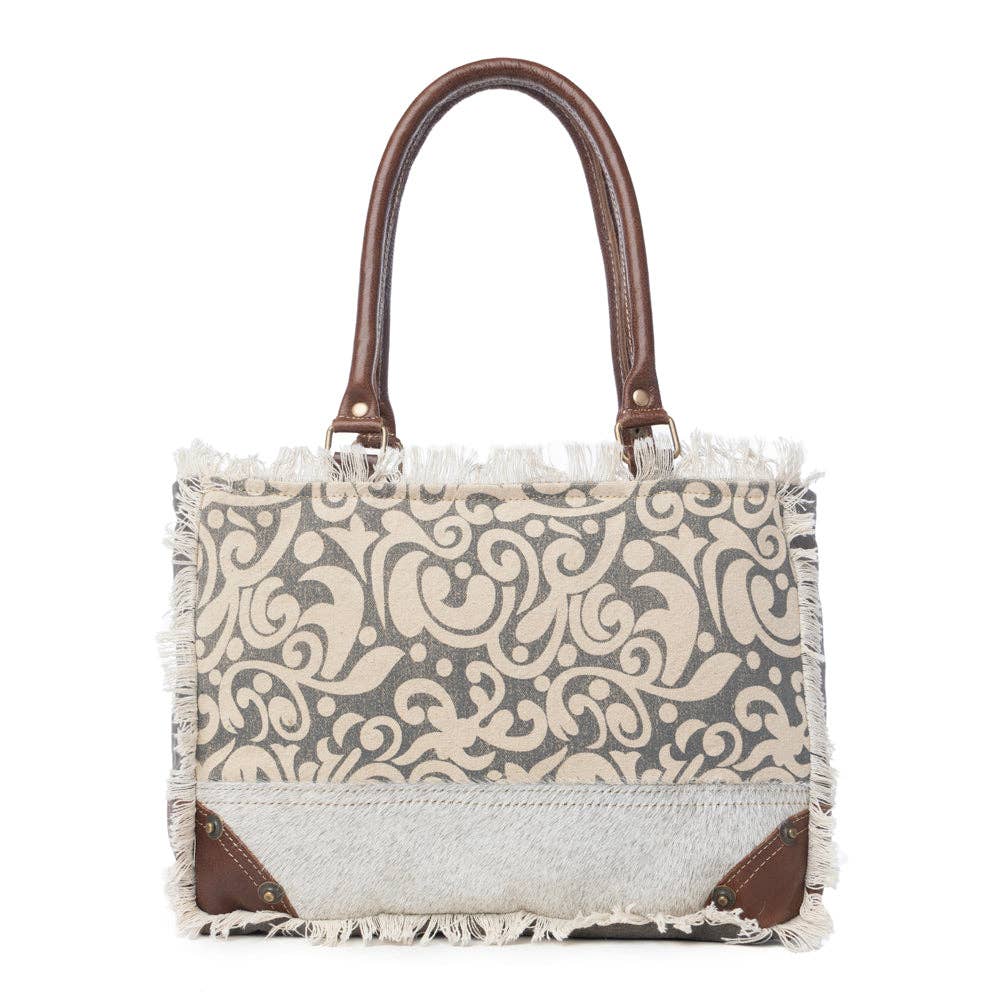 Leaf print small bag with a canvas body, leather accents, large main compartment, and zippered pocket inside.