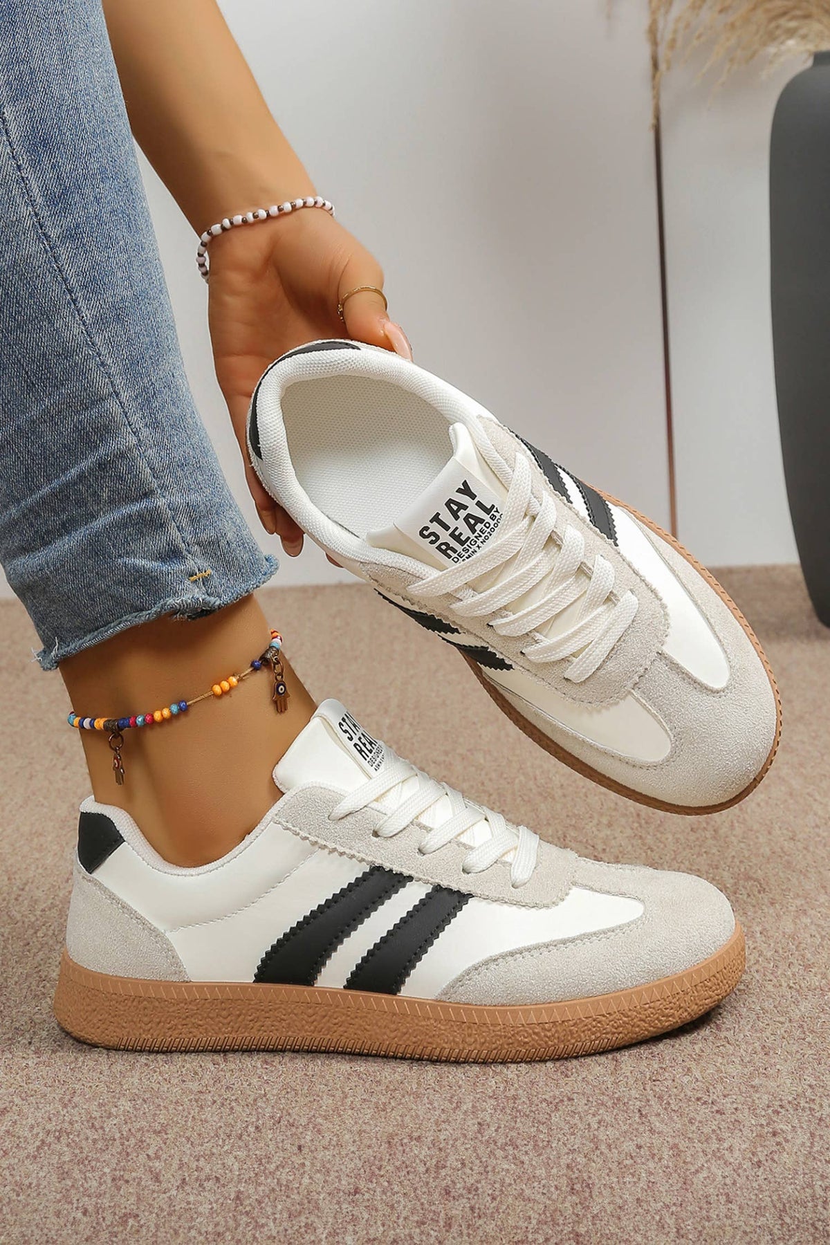 Color block patchwork sneakers in white, black, and light gray with a low-top silhouette and textured sole.