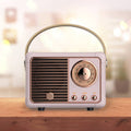 Retro mini wireless Bluetooth speaker with a front speaker grille, large dial, and control buttons in a stylish design.