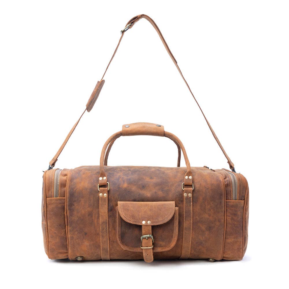 Amber brown leather traveller bag with a structured shape, top handle, detachable shoulder strap, and visible side pockets.