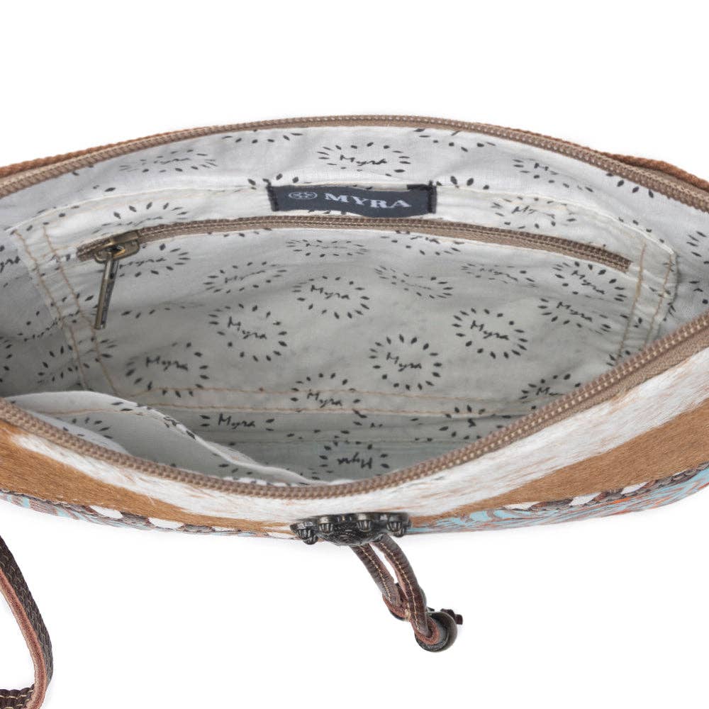 Turquoise embossed leather crossbody bag with brown-and-white cowhide accent and a zippered pocket inside.
