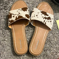 Brown and cream cow print sandals with a comfortable slip-on style, perfect for everyday wear.